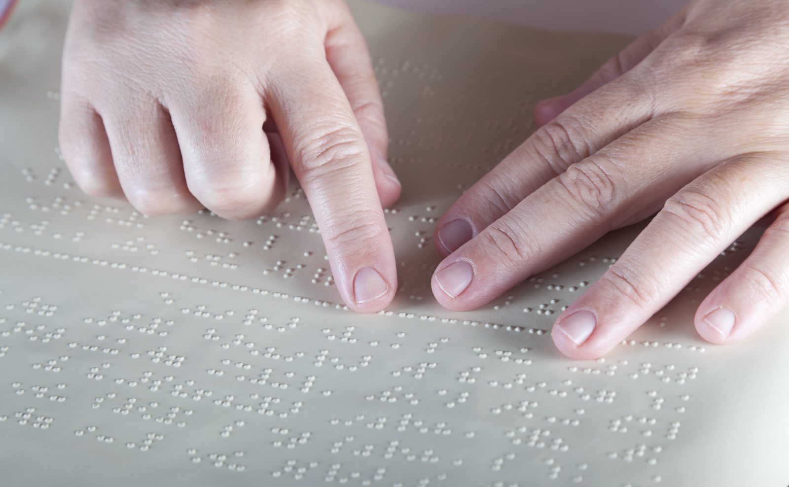 A close up of hands reading a braille document.