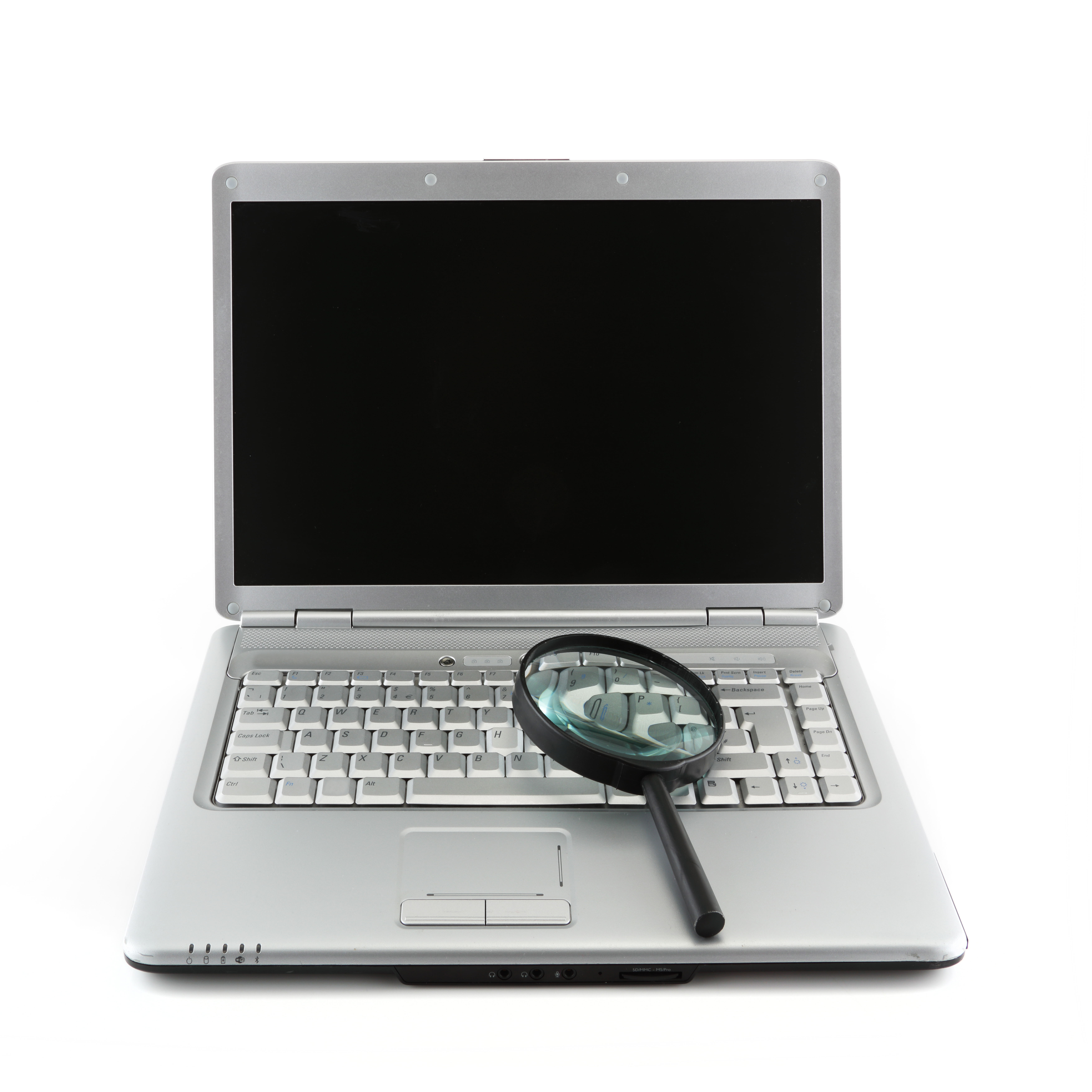 An open laptop with a magnifier sitting on the keyboard.